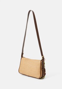 Tkaný slaměný crossbody batoh s obdélníkovým tvarem, hnědým koženým zakončením, nastavitelným popruhem, zlatým kováním a barevným akcentem v podobě přívěsku.