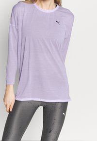 Light purple long-sleeve athletic top with a round neckline and black logo. Paired with gray leggings featuring a subtle texture.