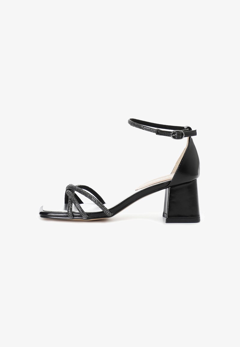 Mustat korkokenkä-sandaalit, joissa on nilkkaremmimalli, neliön muotoinen kärki ja tekstuuriset mustat remmit. Korko on lohkomainen muotoilu, joka tarjoaa vakautta ja tukea.