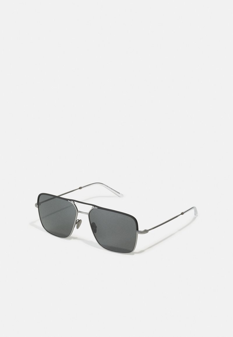 Óculos de sol com um design de lente retangular escura, armação de metal em prata e preto, hastes finas e almofadas para o nariz. Texturas mate e brilhante presentes.