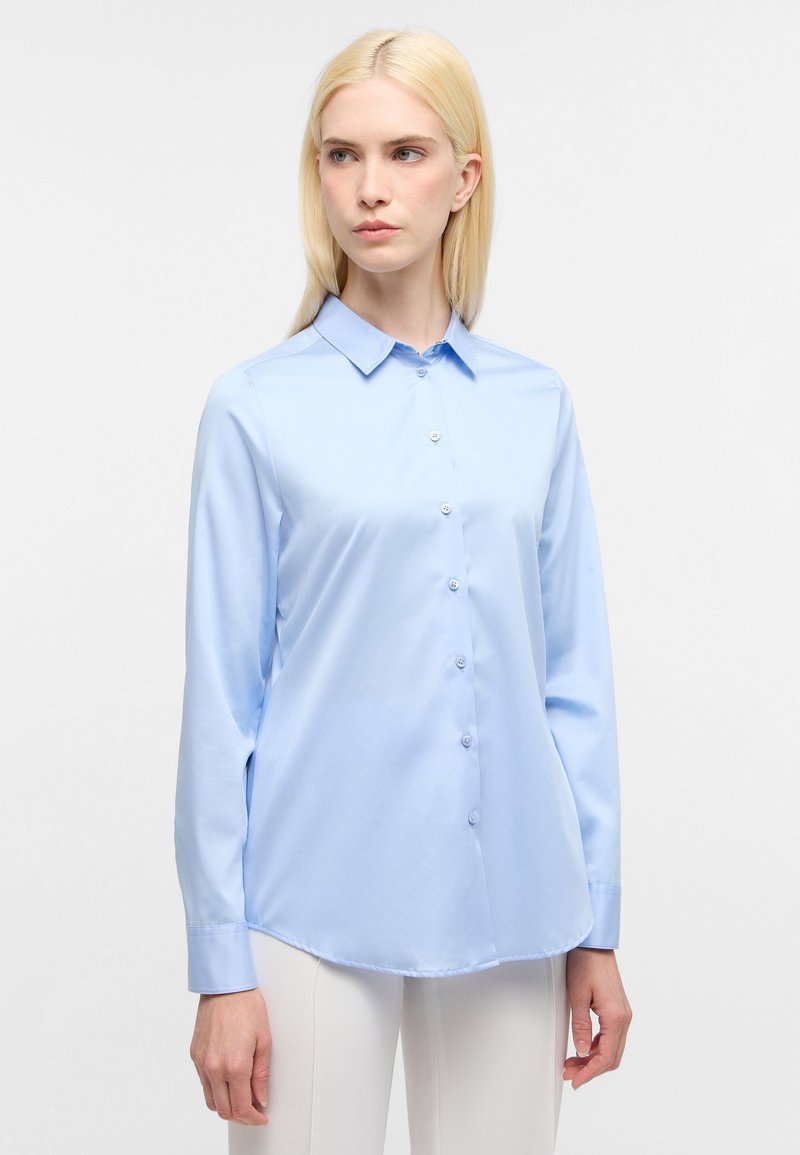 Camicia a maniche lunghe azzurro chiaro con colletto a punta, chiusura frontale con bottoni e texture liscia, dotata di orlo curvo e polsini bottone.