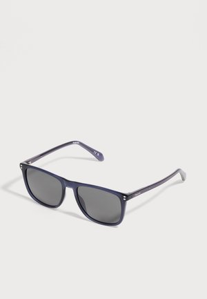 Gafas de sol rectangulares con montura azul oscuro y lentes polarizados negras, descansando sobre una superficie clara, ligeramente inclinadas hacia la derecha.