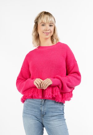 Lyserød, strikket sweater med lange, frynsede bølger ved kanten. Har en rund halsudskæring og en struktureret, ribbet krop. Lange ærmer og tætsiddende manchetter.