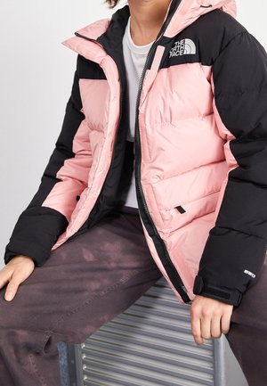 Roze en zwarte pufferjack met een ritssluiting aan de voorkant, verstelbare manchetten en logo-accenten; de doorgestikte structuur voegt textuur toe.