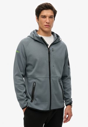Grey zip-up hoodie made from soft material, featuring a hood, two zipped side pockets, and contrasting black hardware accents.