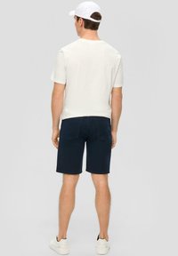 Granatowe szorty dżinsowe i jasnoszara koszulka z krótkim rękawem. Koszulka ma okrągły dekolt, a szorty mają tylne kieszenie.