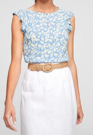 Top azul con estampado floral, mangas con volantes y detalle de abertura en forma de lágrima, combinado con un cinturón tejido beige y una falda blanca de lino.