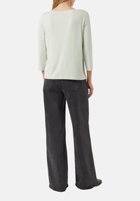 Jasnozielony długi rękaw, miękki materiał, luźny krój, w połączeniu z luźno dopasowanymi ciemnoszarymi dżinsami z tylnymi kieszeniami i prostym przeszyciem.