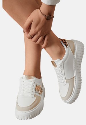 Baskets blanches avec des accents beiges et un imprimé léopard texturé sur le talon. Présentent un design à lacets et une semelle blanche épaisse.
