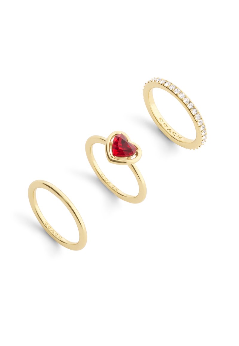 Three gold rings: a plain band, a heart-shaped red stone setting, and a band with clear, set stones along the top edge.