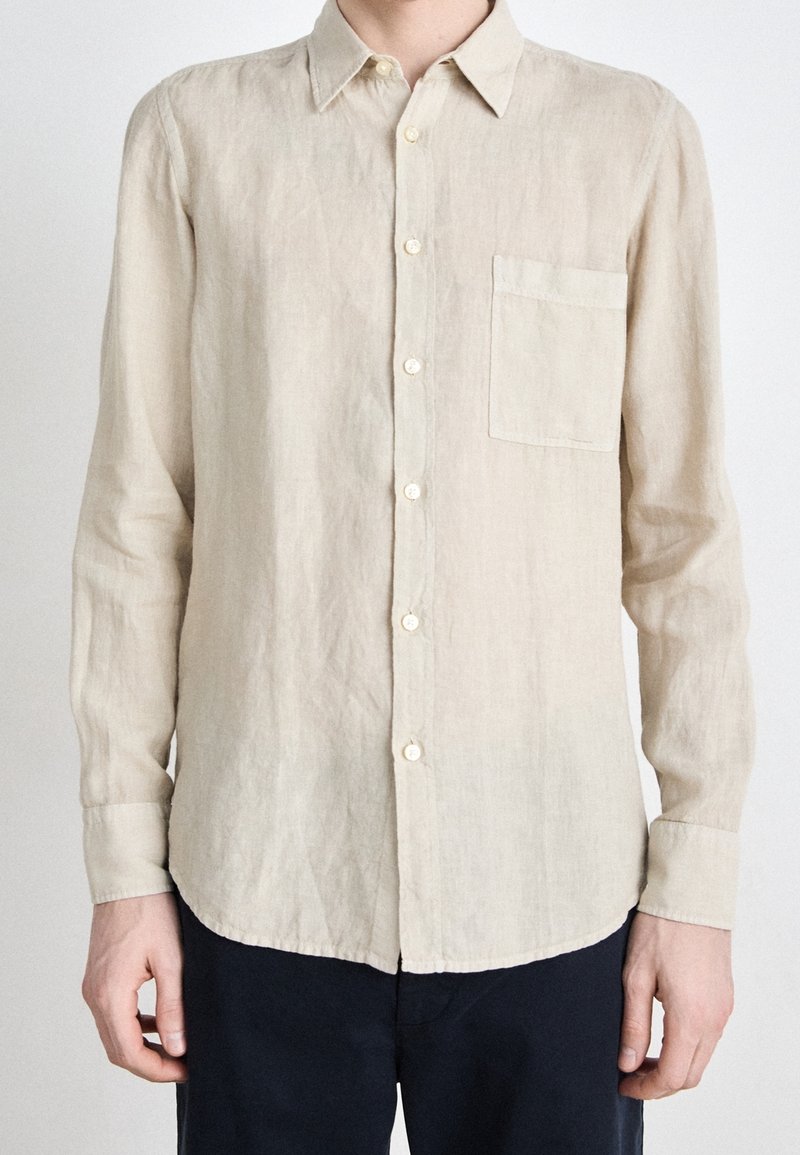 Camicia di lino beige chiaro con maniche lunghe, design con bottoni, colletto a punta e una tasca sul petto. Tessuto liscio, orlo curvo.