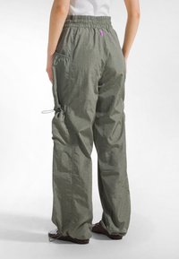 Letvægts olivengrønne bukser med elastik i taljen og mesh-lomme detaljer; løs pasform med justerbar snøre ved anklerne.