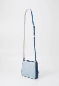 Denim crossbody bag with light and dark blue sections, a white adjustable strap, and silver hardware. Features a zippered main compartment.