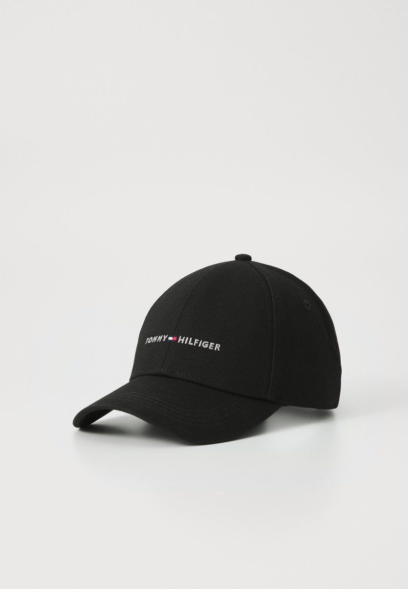 Black baseball cap, cotton material, curved brim, embroidered "TOMMY HILFIGER" logo in white and red on front, smooth texture, adjustable strap.