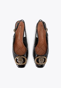 Black patent leather slingback shoes with a textured surface, round gold-tone buckle accent, and quilted brown insole.