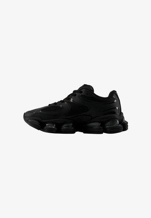 Baskets de sport noires avec tige en mesh et synthétique, lacets à l'avant et semelle épaisse segmentée conçue pour l'amorti et le maintien.