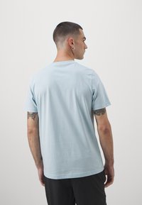 Camiseta de algodón azul claro con cuello redondo clásico y mangas cortas, que presenta una textura suave y un corte relajado.