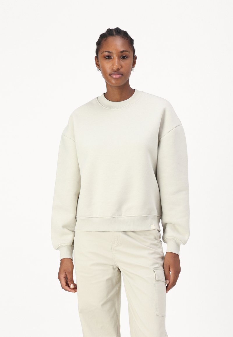 Sweatshirt de algodão cinza claro com decote redondo, ombros caídos e punhos em ribana. Apresenta uma etiqueta de logo discreta na bainha.