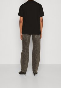 Svart bomulls t-shirt med korta ärmar, kombinerad med högmidjade, urblekta grå jeans med rak passform och subtilt strukturerat mönster.