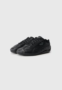 Pantofi atletici negri din piele sintetică cu o textură netedă, cu vârfuri rotunde, sistem de închidere cu șireturi și accente cu logo-ul Puma.