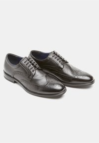 Zapatos de vestir de cuero negro con un acabado suave, diseño de punta alada, perforaciones decorativas y una puntera pulida, con cierre de cordones.