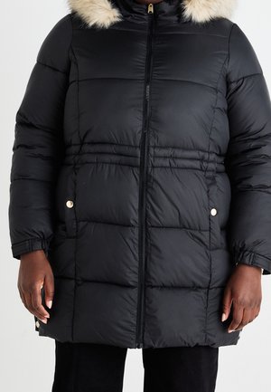 Czarna pikowana zimowa kurtka z przednim zamkiem błyskawicznym, bocznymi kieszeniami na guziki, elastycznymi mankietami i kapturem obszytym futerkiem, noszona przez osobę.