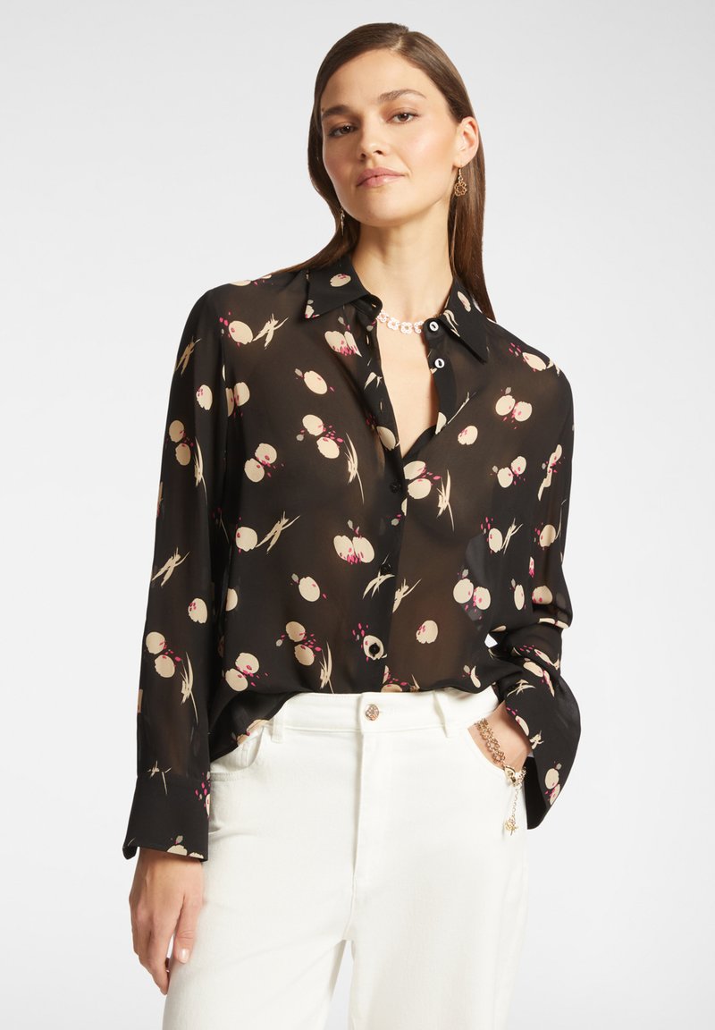 Camicia nera a maniche lunghe in tessuto leggero con un sottile motivo floreale in beige, rosa e verde. Presenta un colletto e una chiusura con bottoni.