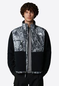 Kurtka polarowa z czarną bazą i wzorzystą szarością na górze. Posiada zapinane na zamek kieszenie oraz wysoki kołnierz zapewniający ciepło. Teksturowana tkanina.