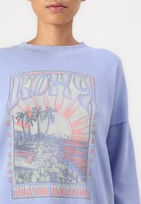 Lichtpaarse longsleeve top met een grafisch print van een strandscène met palmbomen, zon en tekst. Gemaakt van textuurstof.