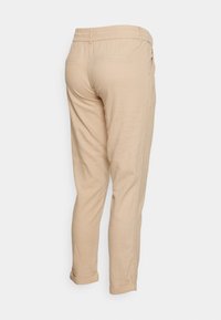 Pantaloni beige con cintura elastica, gambe affusolate e risvolti. Dotati di due tasche posteriori e una texture di tessuto liscia.