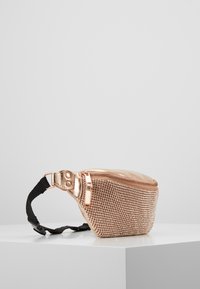 Borsetta metallica color oro rosa con superficie strutturata impreziosita da piccole borchie, chiusura con zip e tracolla nera regolabile per il uso a spalla.