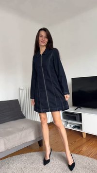 Denimkjole i mørk blå med glidelås foran, krage, lange ermer og kontrastsømmer. Brukes med svarte høye hæler.