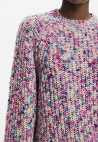 Sweter dzianinowy z teksturowanym wzorem w odcieniach różu, niebieskiego i kremowego. Okrągły dekolt i opadające ramiona podkreślają przytulny wygląd.
