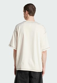 T-shirt crema a vestibilità morbida con maniche corte, dettagli di cucitura visibili e scollo rotondo, realizzato in morbido cotone.