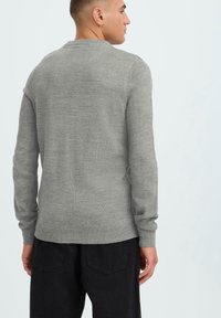 Gray wool sweater with a crew neckline, long sleeves, and ribbed hem. Visible texture with a smooth finish and minimalist design.