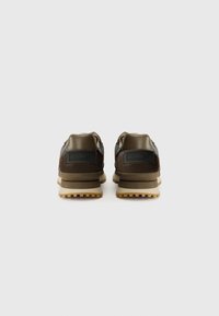 Sneaker marroni e neri con parte superiore testurizzata, colletto imbottito e suola in gomma. Presenta un dettaglio del logo sul tallone e un sistema di allacciatura.