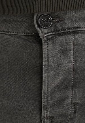 Grijze denim jeans met een gestructureerde afwerking, voorzien van een zwarte knoopsluiting, subtiele stiksels en een donkere tailleband, die minimalistische ontwerpelementen benadrukt.
