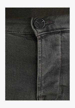 Šedé džíny vyrobené z denimu s texturovaným povrchem, s černým uzávěrem na knoflík, jemným prošíváním a tmavým pasem, které zdůrazňují minimalistické designové prvky.