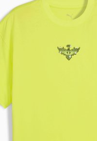 Lys gul t-shirt med et centralt logo med vinger og en halo, der antyder en sportiv eller atletisk stil.