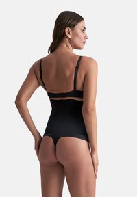 Mustat muotoilevat bodysuitit, joissa on säädettävät olkaimet ja hakasuljenta, sileällä pinnalla ja keskireiteen leikkauksella.
