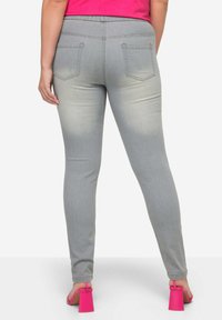 Šedé džínové skinny džíny s texturovaným povrchem, elastickým pasem a dvěma zadními kapsami. Vytvořené s jasně růžovými sandály na blokovém podpatku.