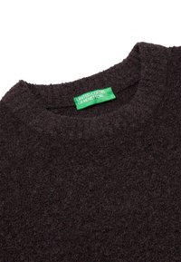 Tmavě šedý svetr s kulatým výstřihem, texturovanou tkaninou a viditelnou zelenou visačkou označenou "United Colors of Benetton."