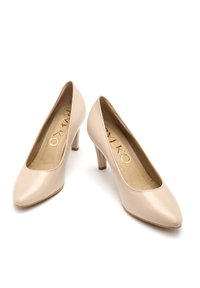 Beżowe lakierowane szpilki z okrągłym noskiem, 7,5 cm obcasem w kształcie bloku i wytłoczonym złotym logo na wkładce. Gładka tekstura.