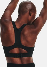 Sujeción deportiva negra con un diseño de espalda en forma de Y, que presenta una parte trasera abierta y cut-outs de malla para mayor transpirabilidad. Tela texturizada y cerraduras de tirantes ajustables.