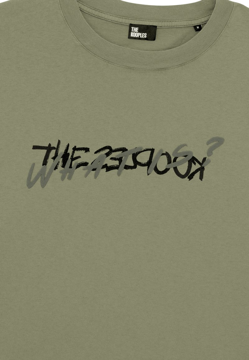 Camiseta de algodón verde oliva con un diseño de texto gráfico en negro y gris ligeramente difuminado, con cuello redondo y mangas cortas.