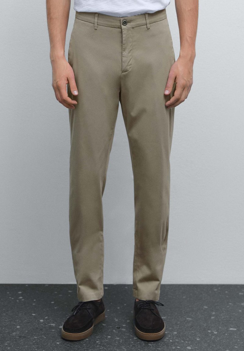 Beige chinos i mjukt tyg med dragkedja och enkel knappstängning. Matchat med mörkbruna mockaskor.