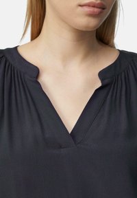 Zwarte blouse met een V-halsontwerp, zachte textuur, gatherings bij de schouders en minimalistische styling, met focus op een gladde stofafwerking.