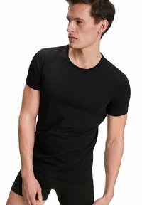 Czarny t-shirt z krótkim rękawem wykonany z miękkiej bawełny, z okrągłym dekoltem i dopasowanym krojem, zaprezentowany na modelu na neutralnym tle.