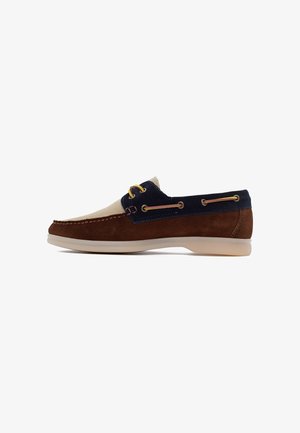 Męskie casualowe buty typu boat shoe z brązowymi, granatowymi i beżowymi panelami z zamszu, żółtymi sznurowadłami i jasnobeżową gumową podeszwą, widok z boku na białym tle.