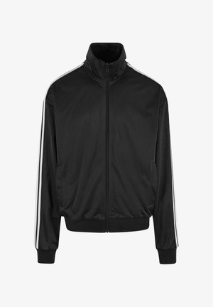 Veste de sport zippée noire avec col haut, rayures blanches sur les côtés, poignets élastiques et texture lisse. Deux poches latérales incluses.